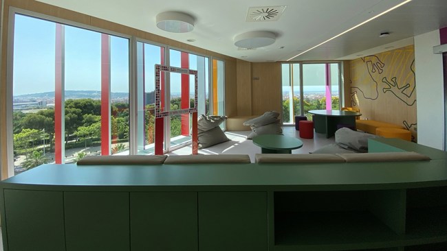 A room with multicolored furniture looking out on a verdant landscape