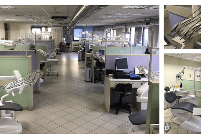 A large room is divided into cubicles with dental chairs and the attendant implements