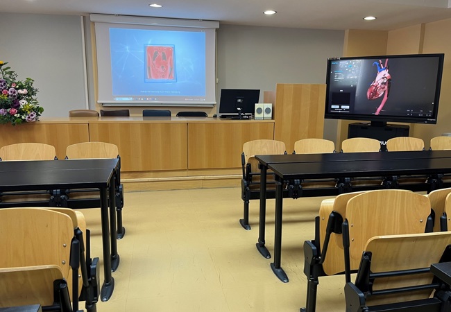 A classroom with chairs and a projector screen for presentations and the anatomage table.