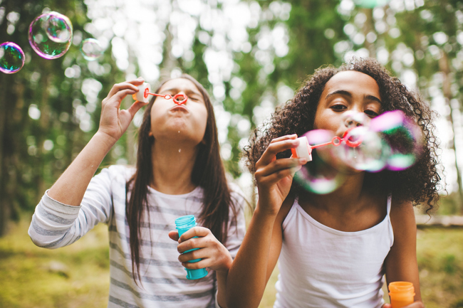 Two children blow bubbles outdoors